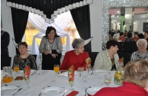 Przy stole siedza i stoja kobiety