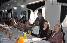 Kobiety siedza za stolem, rozmawiaja, usmiechaja sie.