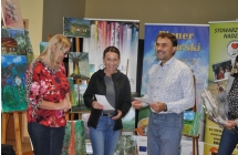 Usmiechniete dwie kobiety i mezczyzna na tle banerow i obrazow