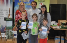 Troje doroslych przed ktorymi stoi trojka dzieci z dyplomami