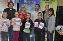 Usmiechnieci dorosli i dumnie pozujacy dzieci z dyplomami