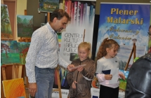 Mezzyzna wreczajacy usmiechnietej dziewczynce dyplom