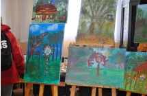 Obrazy w ciemnych odcieniach wystawione w sali