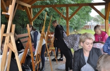 Kobieta oraz dziewczynki malujace obrazy nasztalugach