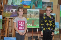 Dziewczynka i chlopiec pozujacy do zdjecia przy sztalugach