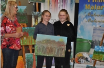 Dwie usmiechniete dziewczynki trzymajace wyjatkowy obraz