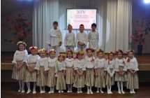 Kilkanascie dziewczynek w ludowych strojach i czworo chlopcow