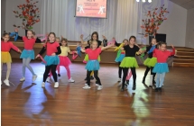 Kilkanascie pieknych dziewczynek w kolorowych strojach tanczacych na parkiecie